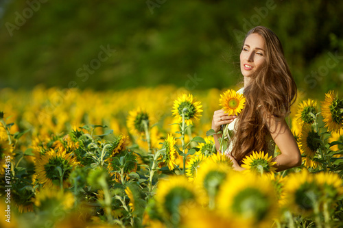 Sunny day woman in a field among blooming sunflowers.