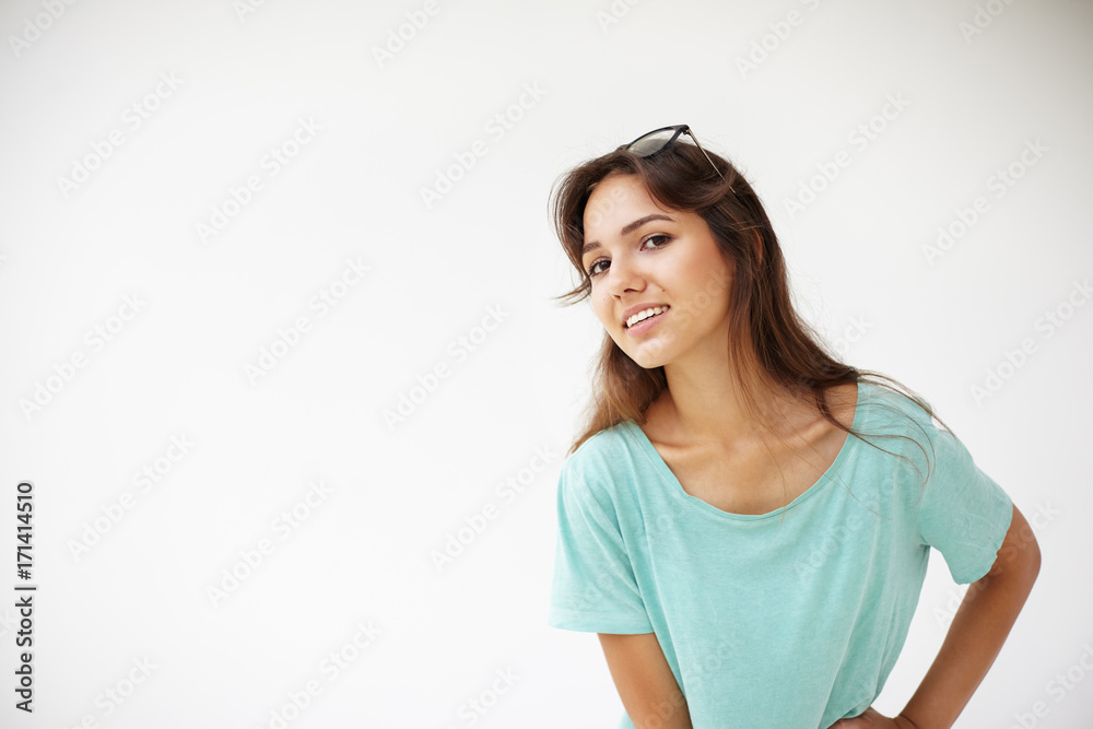 People, youth, leisure and lifestyle. Cute brunette young mixed race female student wearing oversize blue t-shirt and glasses on head smiling happily, having rest at home after lectures at college People, youth, leisure and lifestyle. Cute brunette young mixed race female student wearing oversize blue t-shirt and glasses on head smiling happily, having rest at home after lectures at college
