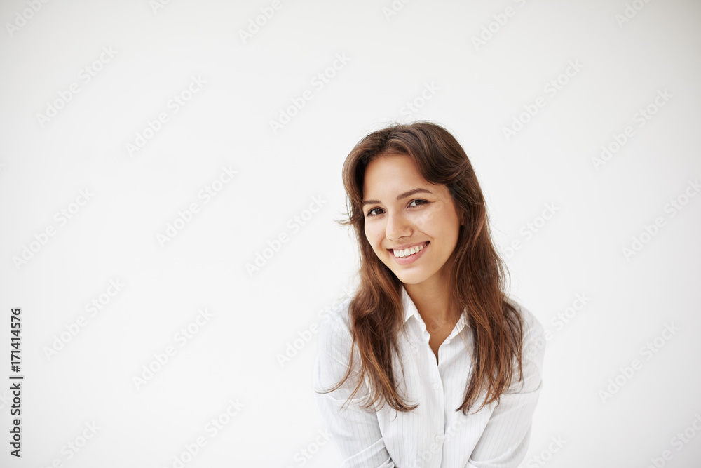 Portrait of beautiful positive young female student, employee or customer with happy friendly smile grinning broadly at camera, showing her perfect straight teeth, posing in studio wearing white shirt Portrait of beautiful positive young female student, employee or customer with happy friendly smile grinning broadly at camera, showing her perfect straight teeth, posing in studio wearing white shirt