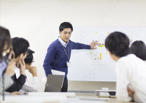 Businessman giving presentation to colleague in office meeting photo
