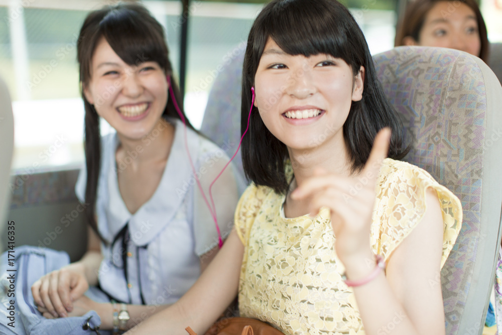 Two Young Women Sharing Headphone on Bus Two Young Women Sharing Headphone on Bus