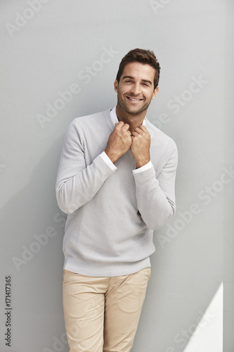Confident smiling guy in grey sweater, portrait