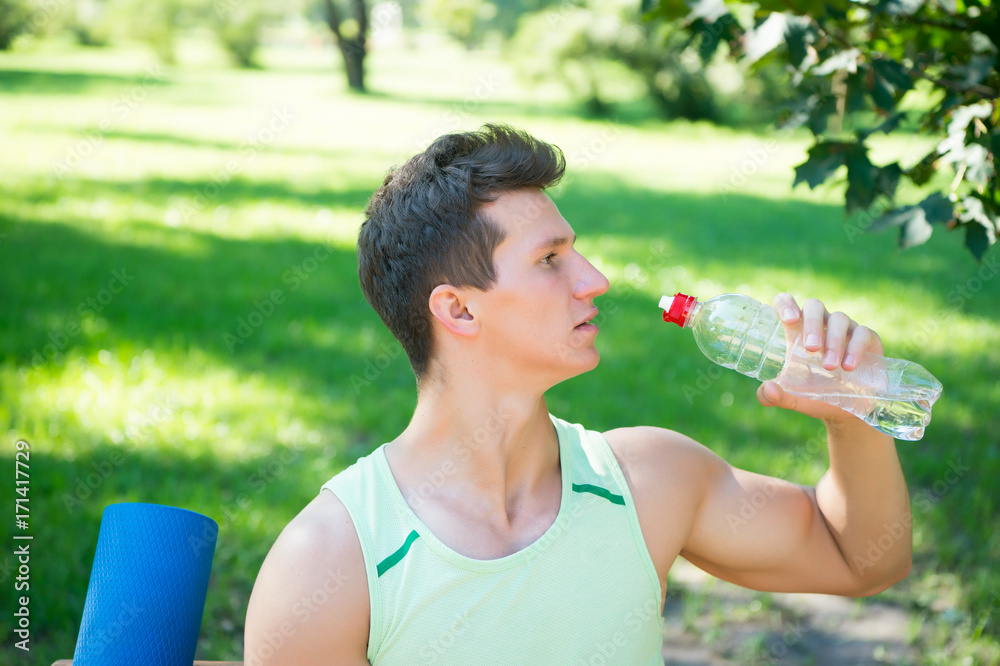 Sportsman drinking water on sunny day on natural summer landscape Sportsman drinking water on sunny day on natural summer landscape