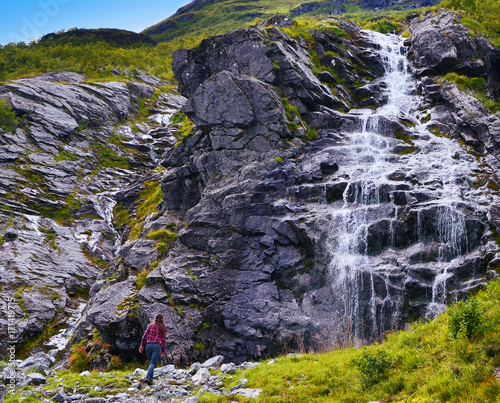 Hjorundfjord, Norway - October 2nd, 2017: Girl hiking to a Waterfall in Sunmore Alps, near Hjorundfjord, Norway photo