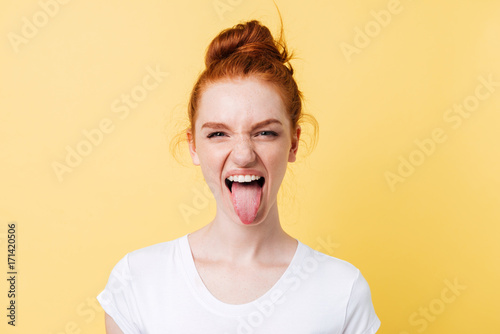 Photo Funny ginger woman showing tongue and looking at the camera