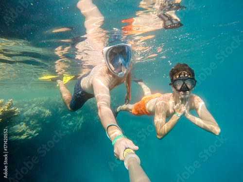 father and son snorkel in shallow water on coral fish