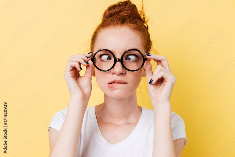 Close-up picture of funny ginger woman in eyeglasess showing grimace - obrazy, fototapety, plakaty 