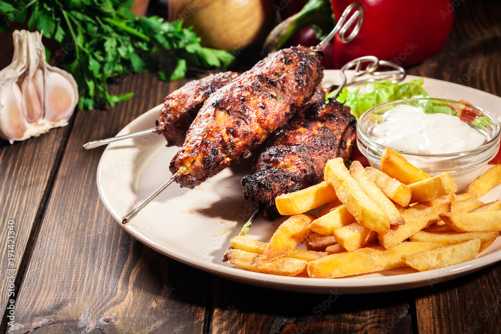 Grilled shish kebab served with fried chips and salad Grilled shish kebab served with fried chips and salad