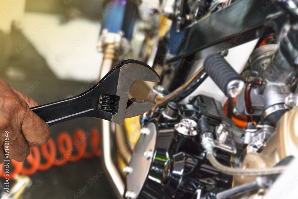 Obraz premium Hand with wrench, Professional mechanic repair and modifications to motorcycle