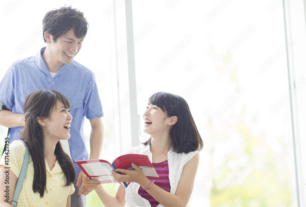 Happy Three College Students Looking at Book Together Happy Three College Students Looking at Book Together