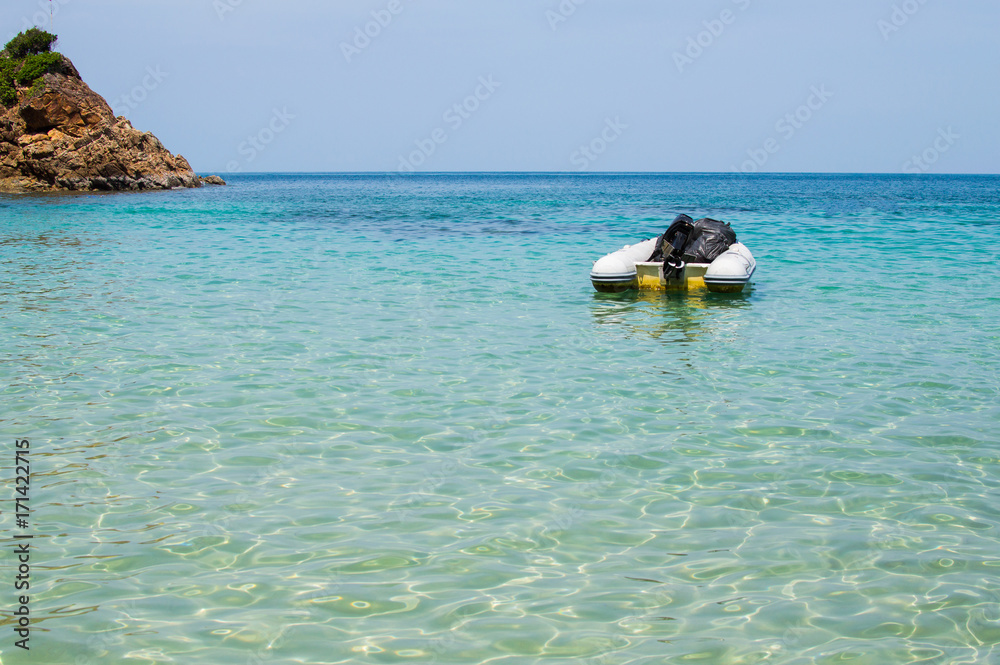 Obraz premium Inflatable dinghy boat with outboard motor moored in tropical sea