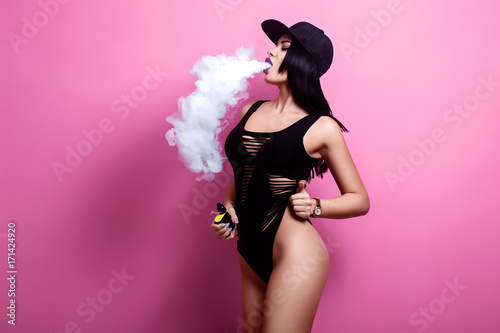 Young sexy woman is vaping. A cloud of vapor. Studio shooting.