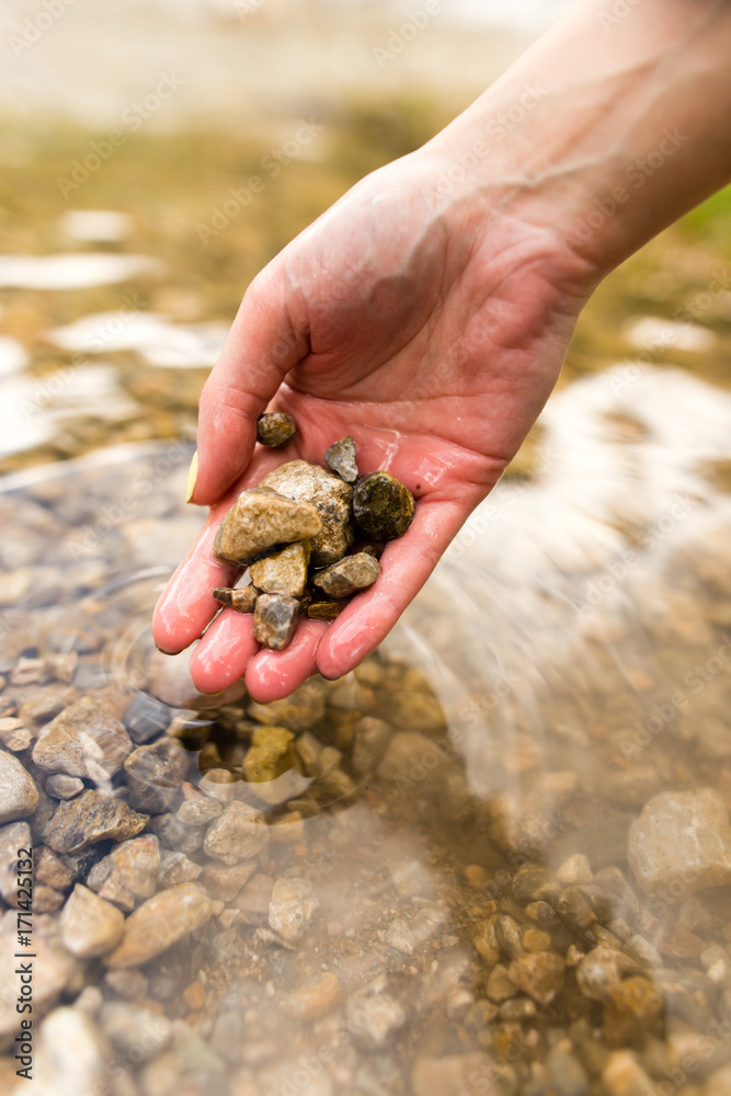 Small stones in the hand on the pond