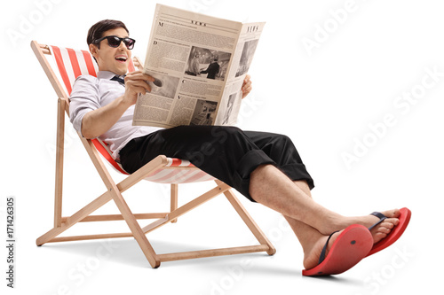 Photography Businessman sitting in a deck chair and reading a newspaper