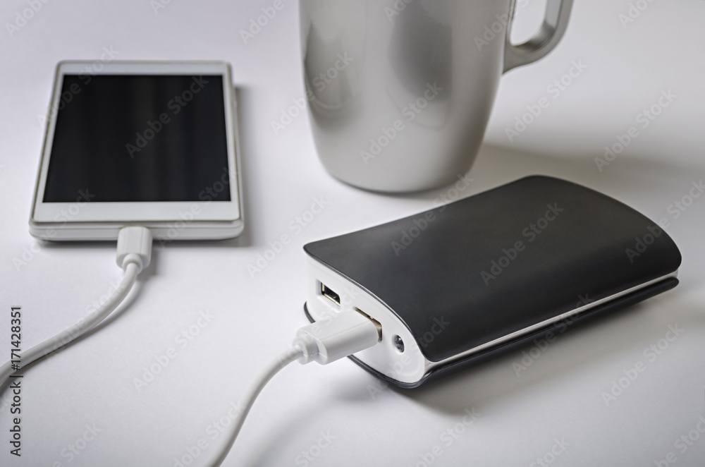 Powerbank charging a smartphone next to a cup of coffee Powerbank charging a smartphone next to a cup of coffee