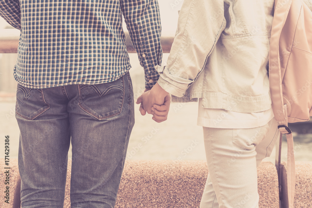 A guy and a girl are holding hands together and looking at the sea