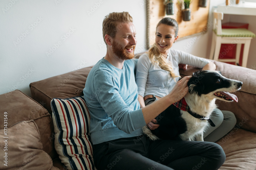 Beautiful couple relaxing at home and loving their dog Beautiful couple relaxing at home and loving their dog