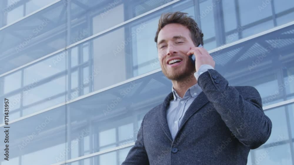 Cell phone - businessman talking on mobile smartphone in city business district. Confident happy young businessman talking on smartphone outdoors. Young urban male professional. RED EPIC SLOW MOTION. Cell phone - businessman talking on mobile smartphone in city business district. Confident happy young businessman talking on smartphone outdoors. Young urban male professional. RED EPIC SLOW MOTION.
