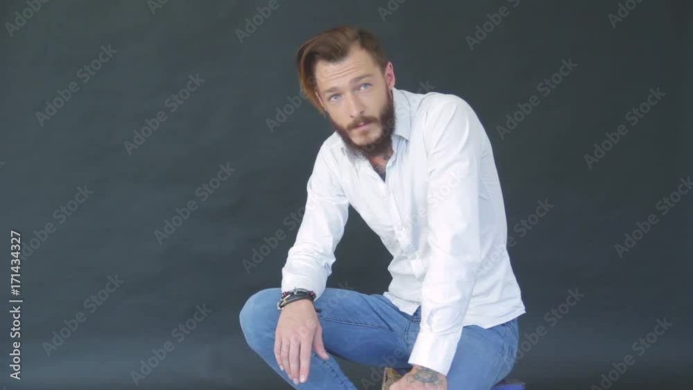 charismatic bearded young man in white shirt on black background in photo studio posing for photographer charismatic bearded young man in white shirt on black background in photo studio posing for photographer