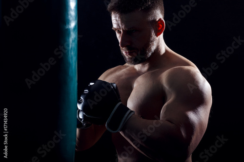 Studio shot of male boxer punching a boxing bag. © Zoran Zeremski