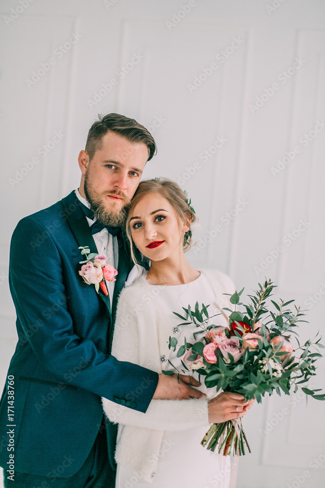 cute wedding couple in the interior of a classic studio decorated. they kiss and hug each other. Newkyweds looking. Bride and groom photoshoot cute wedding couple in the interior of a classic studio decorated. they kiss and hug each other. Newkyweds looking. Bride and groom photoshoot