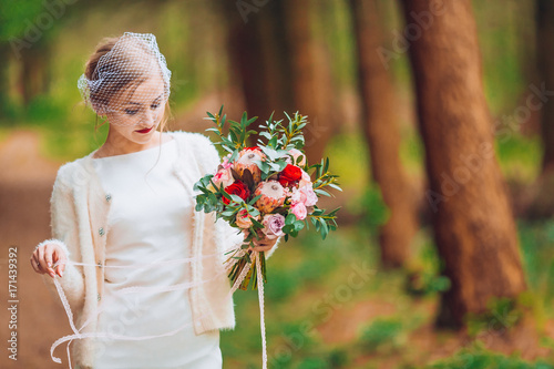 bride with flowers in hand outdoors.