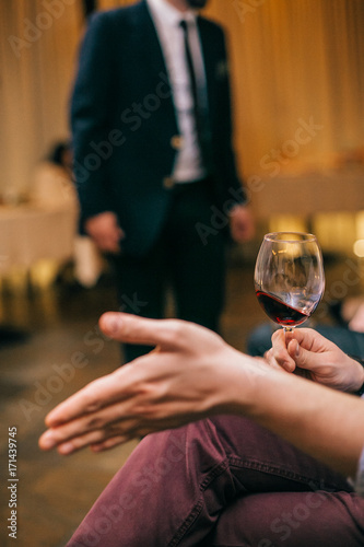 people, alcohol and drinks concept - close up of man hand holding glass with red wine at the party restaurant