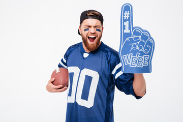 Excited man fan wearing fan glove holding rugby ball.