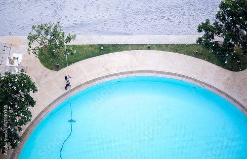Man cleaning swimming pool with Vacuum cleaner