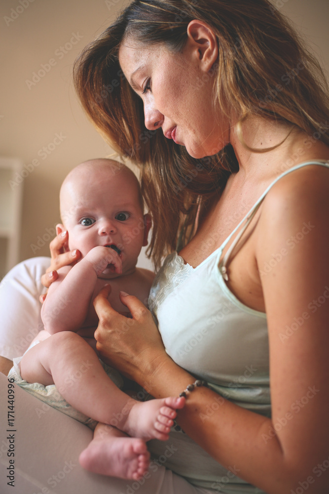 Young mother playing with her baby boy in bed. Mother enjoying in free time with her little cute baby. Young mother playing with her baby boy in bed. Mother enjoying in free time with her little cute baby.