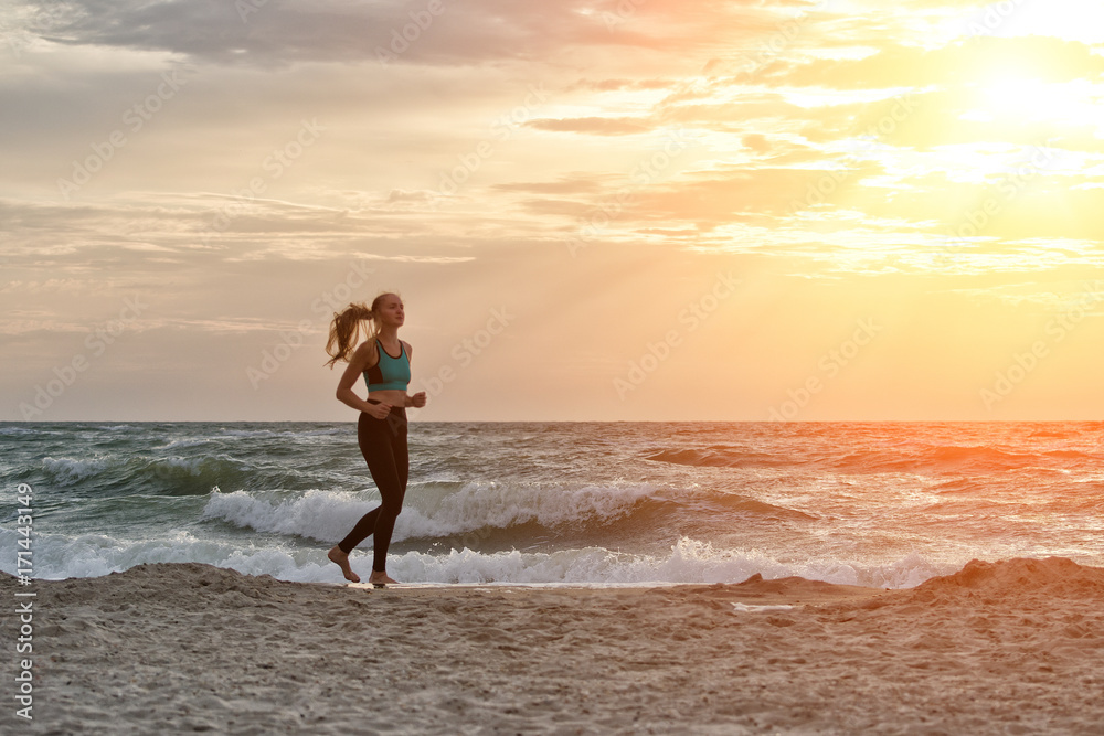 Girl in sportswear running along the surf line. Early morning. Girl in sportswear running along the surf line. Early morning.