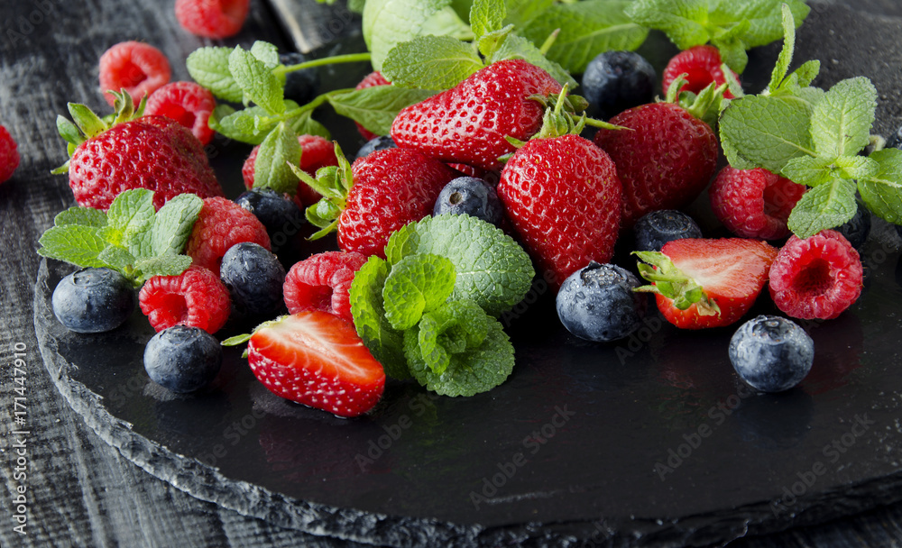 fresh strawberries, raspberries and blueberries on a black background fresh strawberries, raspberries and blueberries on a black background
