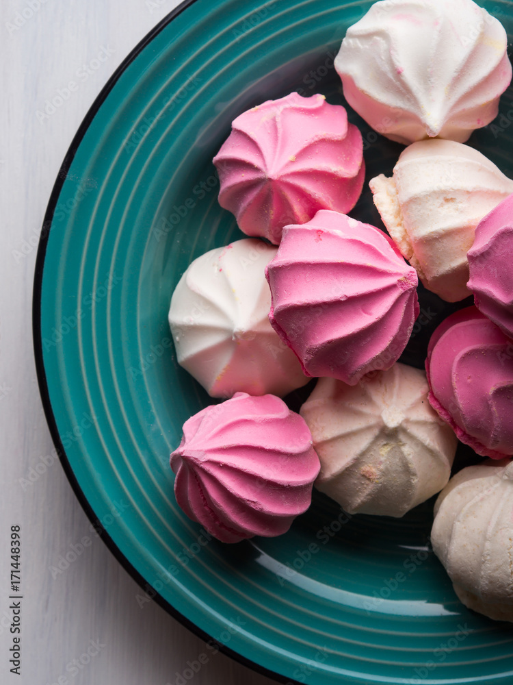 Fototapeta premium Pastel color pink and white meringue on green background
