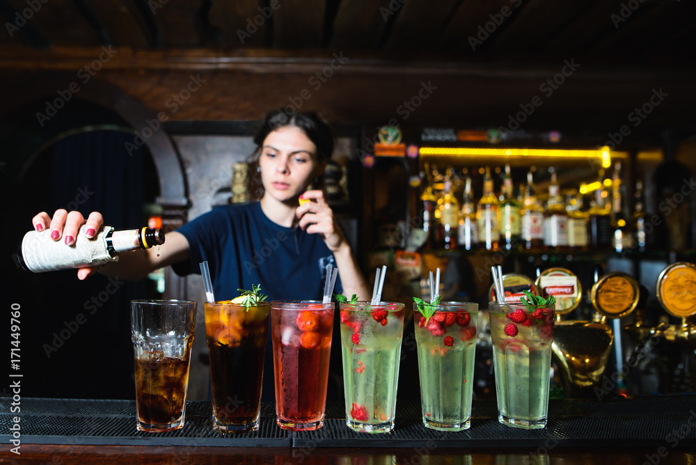 The barman creates beautiful and delicious alcoholic cocktails. Many beautiful alcoholic cocktails at the bar stand. Armenian pours alcohol into a cocktail