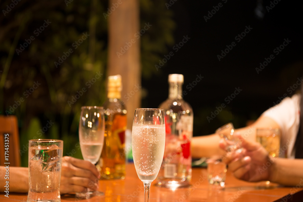 Group of friends enjoying drinking a glass of champagne and whiskey at party