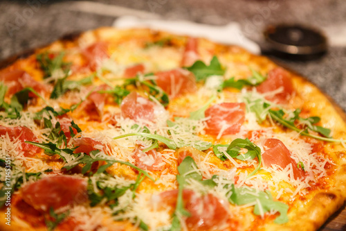 Pizza with prosciutto and rocket salad close up
