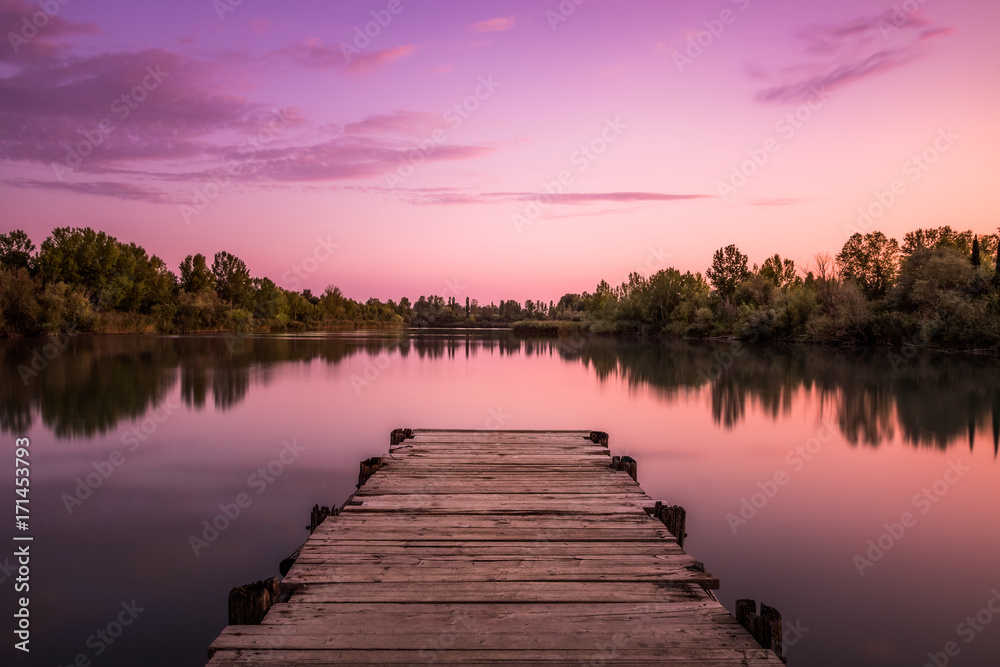 Pier on a lake at sunset in Tuscany