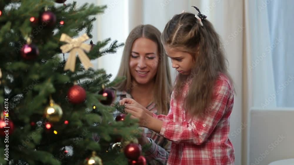 Happy girl with mother decorating Christmas tree Happy girl with mother decorating Christmas tree