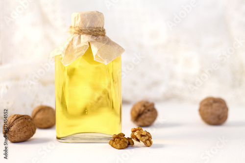 Walnut oil in bottle on white wooden background. Selective focus. photo