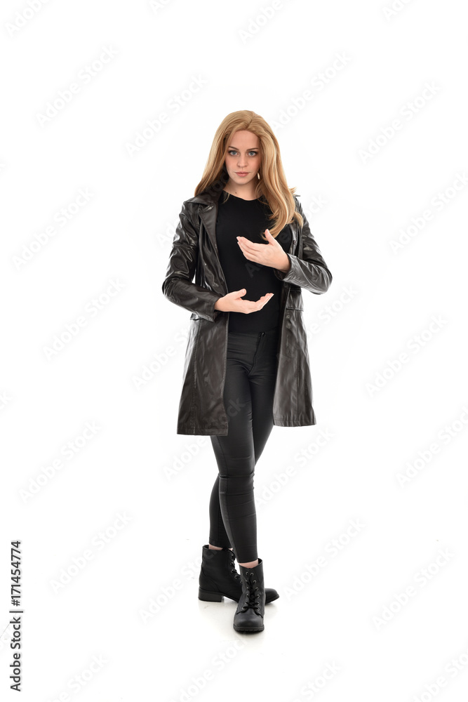 full length portrait of girl wearing black clothes with long leather jacket. standing pose on white background.