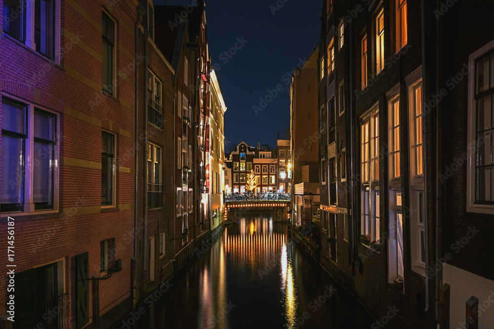 Narrow canal in the old town of Amsterdam in the evening