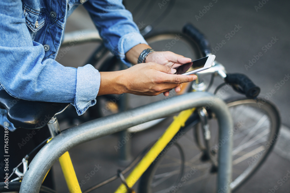 Cropped hands of man using smart phone by bicycle Cropped hands of man using smart phone by bicycle