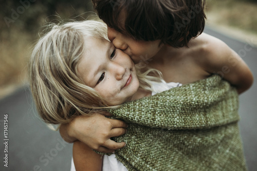 Close-up of brother kissing sister while standing on country road