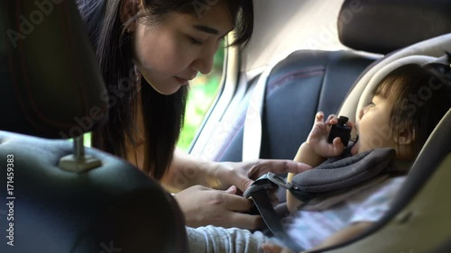 Beautiful asian Mother putting baby in car seat