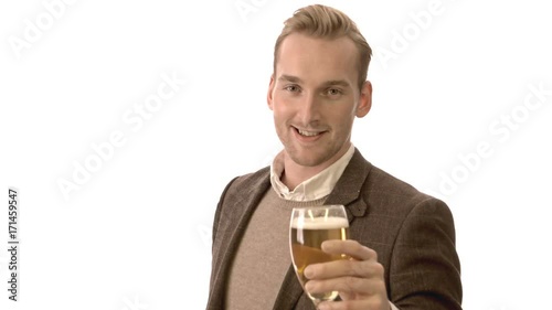 Handsome man in a brown pullover shirt and blazer, holding a glass of beer cheering to camera. White background.