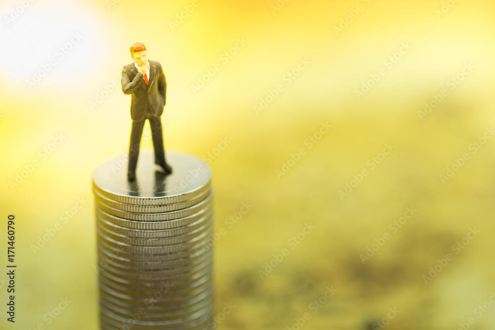Business and money concept. Businessman miniature people figure standing on stack of silver coins. Business and money concept. Businessman miniature people figure standing on stack of silver coins.