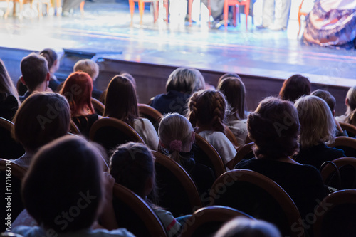 The audience in the theater watching a play. The audience in the hall: adults and children.