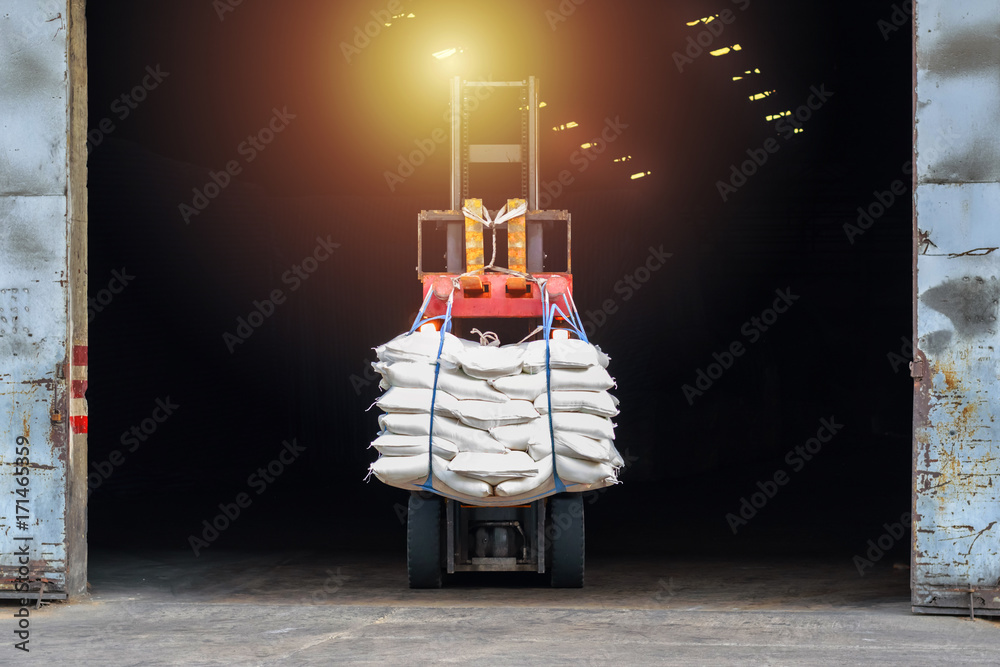 Forklift handling white sugar bags outside warehouse for stuffing into ...