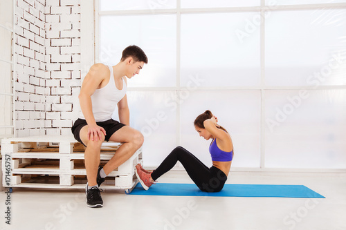 strong young couple working out personal trainer helping woman in gym white background