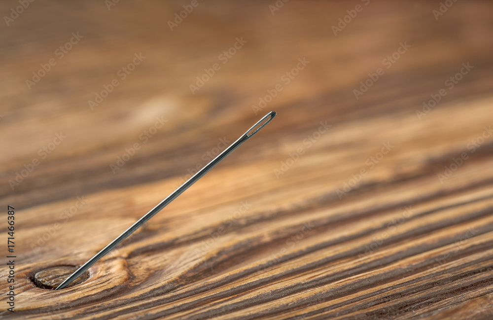wooden background and sewing needle at an angle